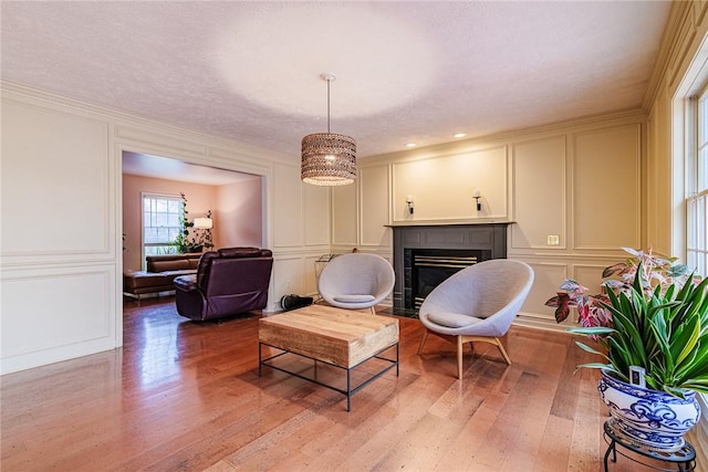 sitting room with light wood-type flooring, a fireplace with flush hearth, and a decorative wall