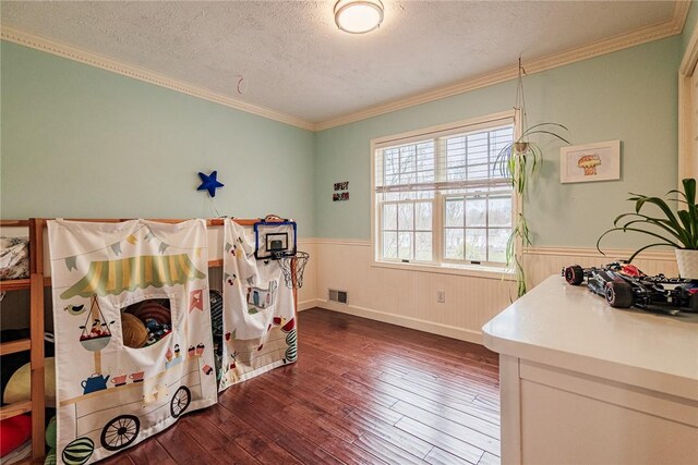 bedroom with wainscoting, dark wood finished floors, a textured ceiling, and visible vents