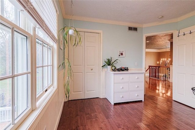 hallway with visible vents, ornamental molding, dark wood-type flooring, and a chandelier