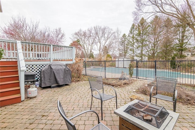 view of patio / terrace with fence, a grill, a fenced in pool, and an outdoor fire pit