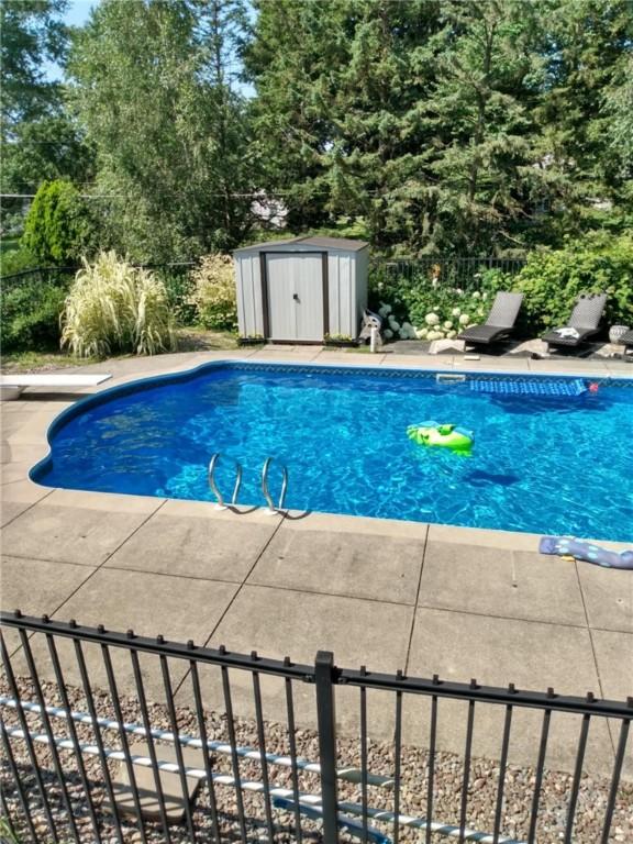 view of pool with an outdoor structure, fence, a shed, and a fenced in pool