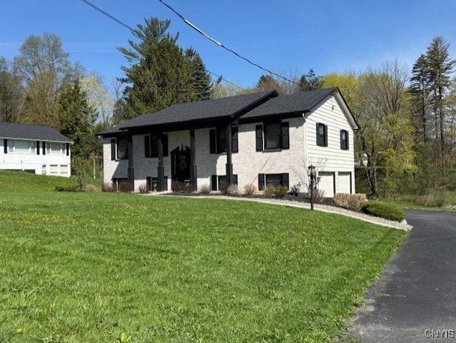 view of front of house featuring a front yard, a garage, and aphalt driveway