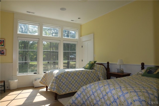 43335 Schoolhouse Rd, Clayton, NY 13624 - bedroom featuring visible vents, wainscoting, and wood finished floors
