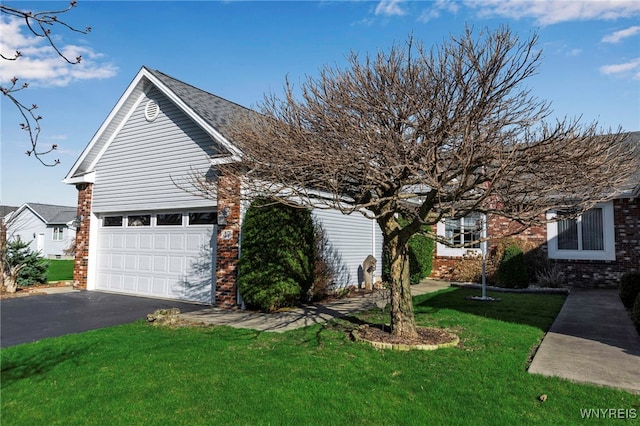 view of side of home with brick siding, aphalt driveway, an attached garage, and a lawn