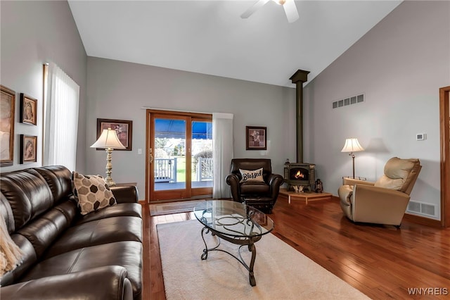 living area featuring a wood stove, visible vents, ceiling fan, and wood finished floors