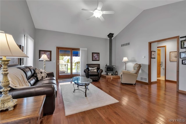 living room with visible vents, a wood stove, ceiling fan, and high vaulted ceiling