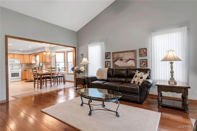 living area featuring a chandelier, baseboards, and light wood finished floors