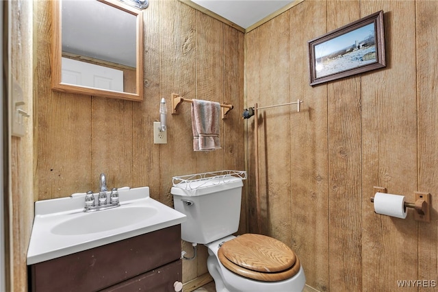 half bathroom featuring wood walls, toilet, and vanity