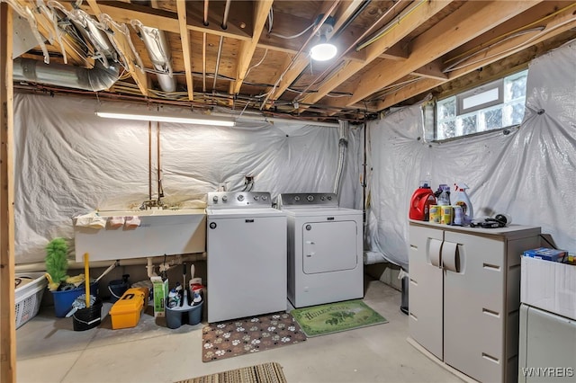 clothes washing area with separate washer and dryer, laundry area, and a sink
