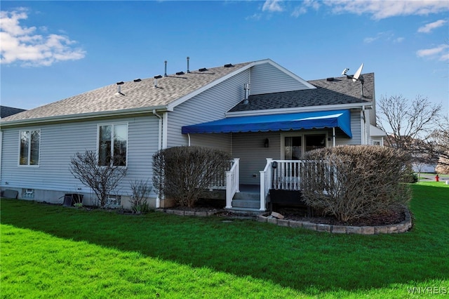 back of house with a yard, a shingled roof, and a wooden deck
