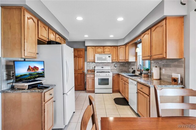 kitchen with dark stone counters, decorative backsplash, a sink, light tile patterned flooring, and white appliances