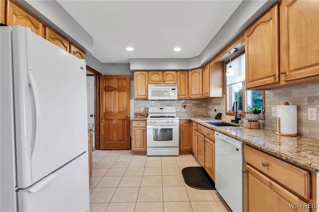 kitchen featuring light tile patterned floors, tasteful backsplash, a sink, light stone countertops, and white appliances