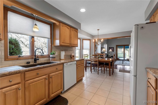 kitchen with a sink, a chandelier, light tile patterned floors, white appliances, and hanging light fixtures