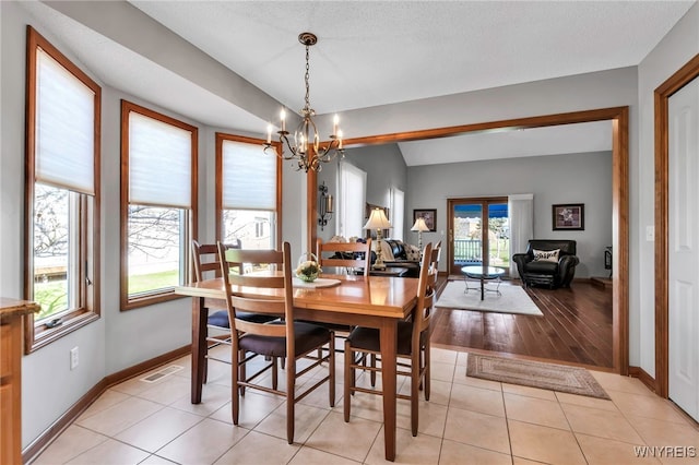 dining area with light tile patterned floors, visible vents, a chandelier, and baseboards