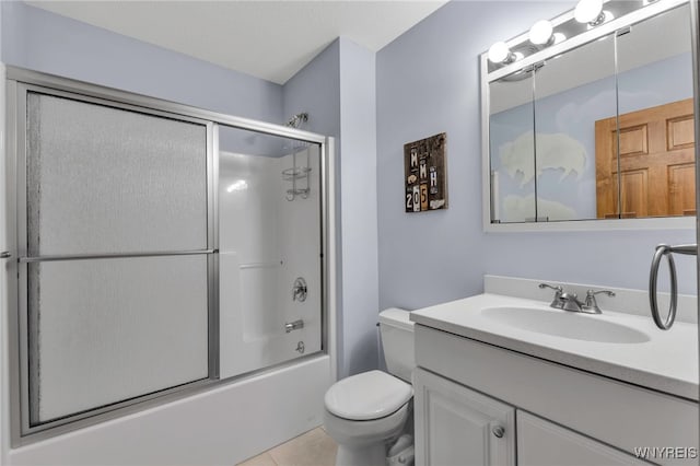 bathroom with tile patterned floors, toilet, vanity, and combined bath / shower with glass door