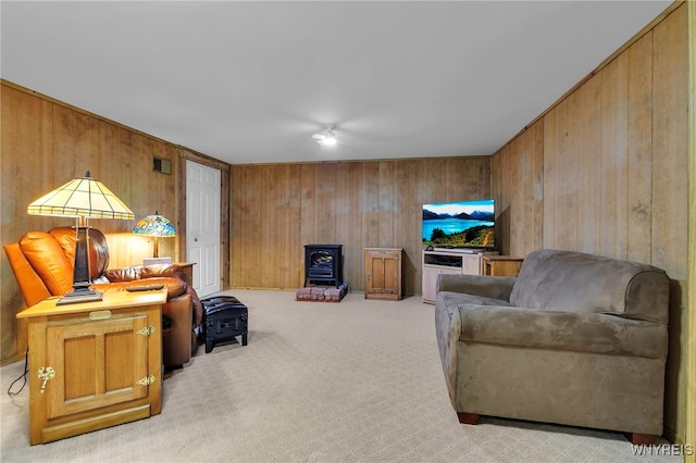 living area with wooden walls, visible vents, and light colored carpet