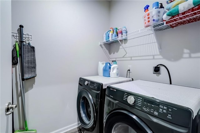 washroom featuring separate washer and dryer, laundry area, and baseboards