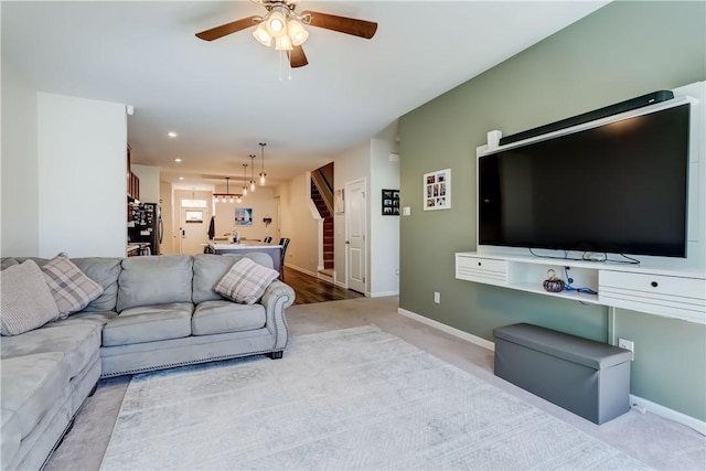 living room featuring baseboards, a ceiling fan, stairs, and carpet floors