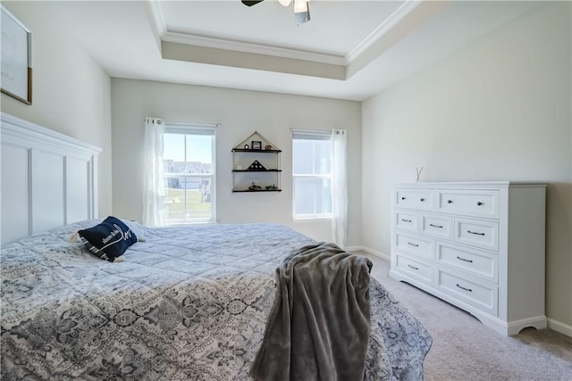 bedroom featuring light colored carpet, a raised ceiling, ceiling fan, baseboards, and ornamental molding