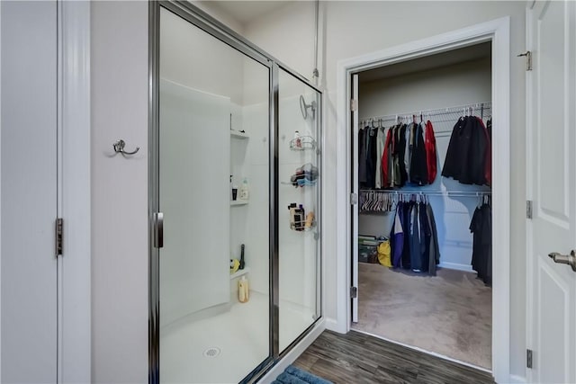 bathroom featuring a shower stall, wood finished floors, and a spacious closet