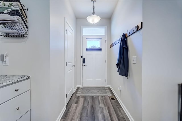 doorway with dark wood-style floors, baseboards, and visible vents