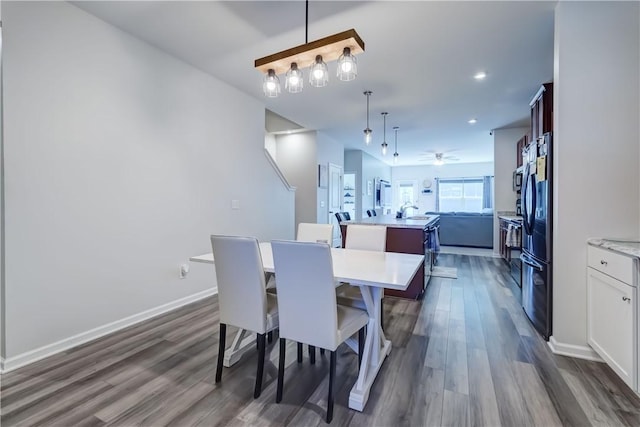 dining space featuring dark wood-style flooring, ceiling fan, and baseboards