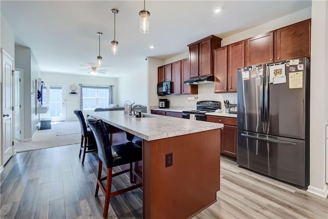 kitchen with a sink, black microwave, light countertops, freestanding refrigerator, and electric range oven
