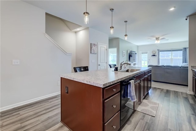 kitchen with a sink, light wood-style floors, light countertops, dishwasher, and open floor plan