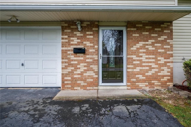 entrance to property with brick siding and a garage