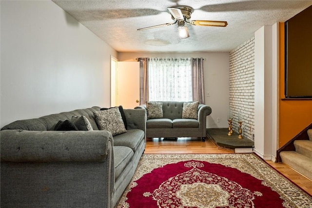 living room with a textured ceiling, a ceiling fan, stairway, and light wood-type flooring