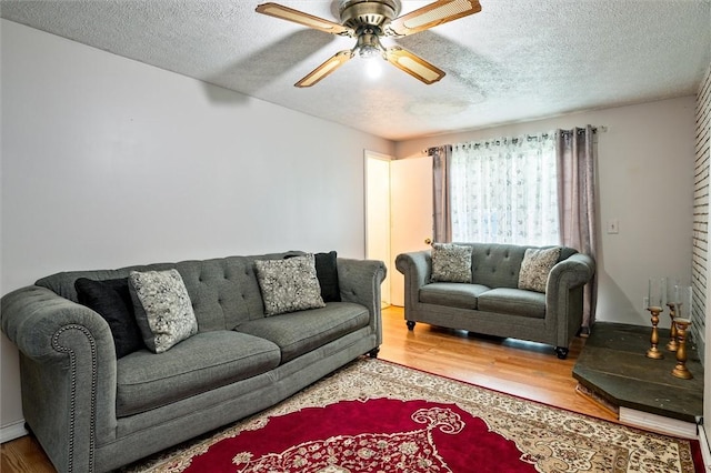 living area featuring wood finished floors, a ceiling fan, and a textured ceiling
