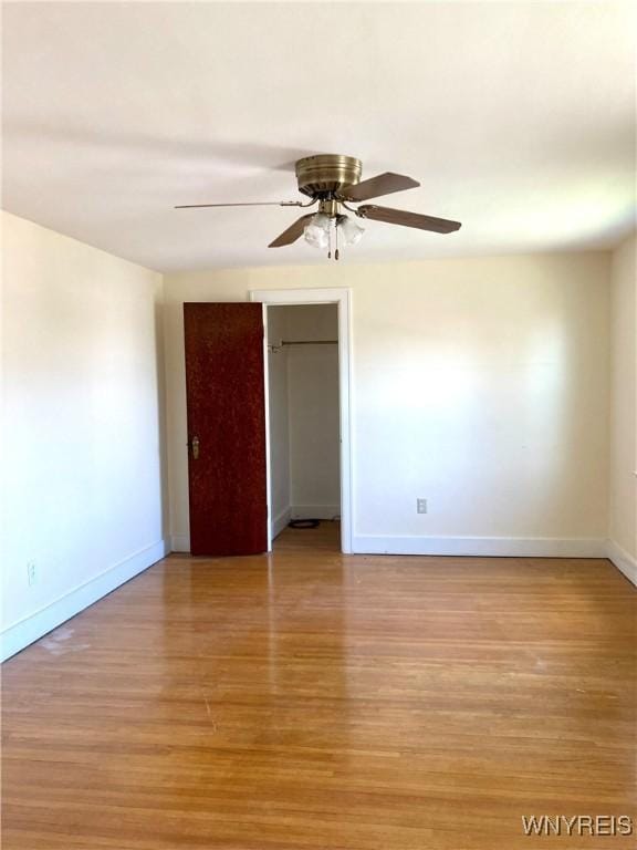 spare room with light wood finished floors, a ceiling fan, and baseboards