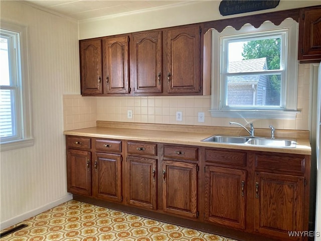 kitchen featuring tasteful backsplash, a sink, light countertops, baseboards, and ornamental molding