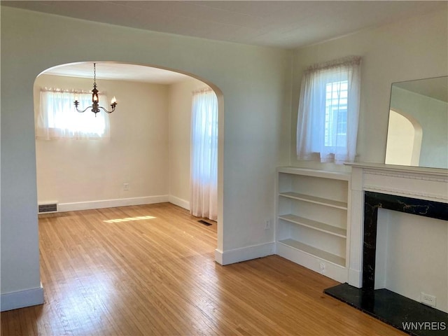 interior space featuring a fireplace with raised hearth, visible vents, wood finished floors, and baseboards