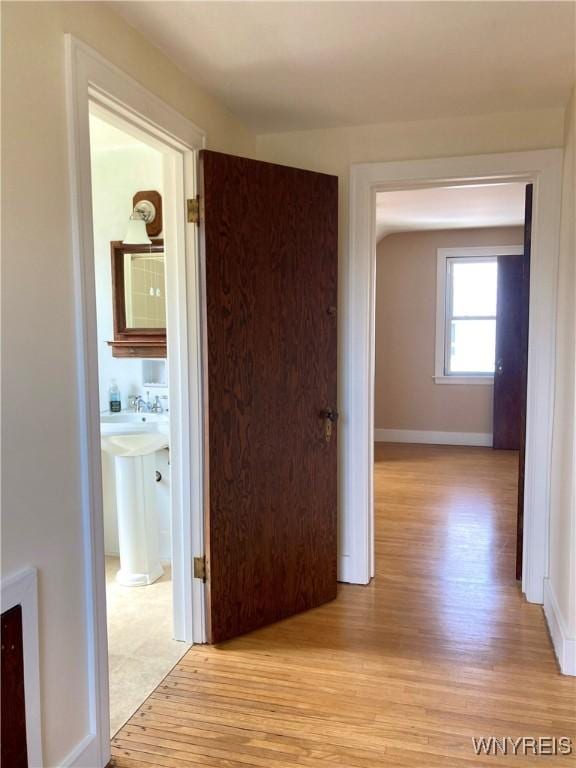 hall with baseboards and light wood finished floors