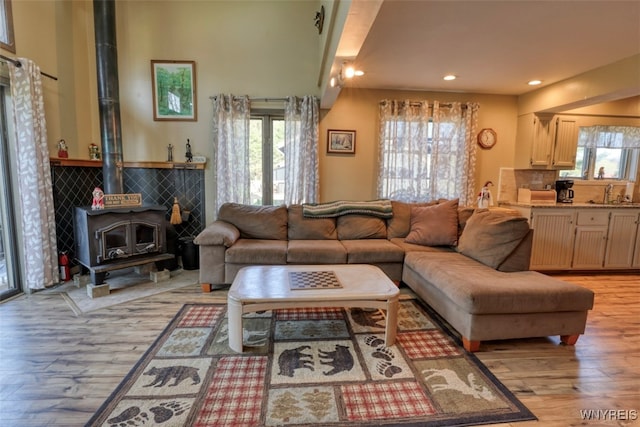 living area with a wood stove, light wood-style flooring, and recessed lighting