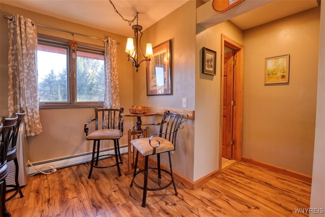 living area with baseboards, wood finished floors, an inviting chandelier, and a baseboard radiator