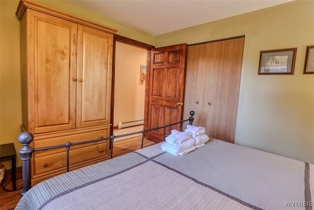 bedroom with a closet, wood finished floors, and a baseboard radiator