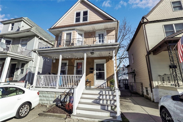 view of front of home featuring covered porch, brick siding, and a balcony