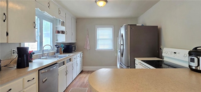 kitchen with stainless steel appliances, light wood-style floors, light countertops, a sink, and white cabinetry