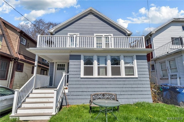 rear view of property featuring a porch and a balcony