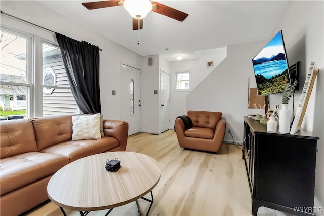 living area with ceiling fan, light wood-type flooring, and baseboards