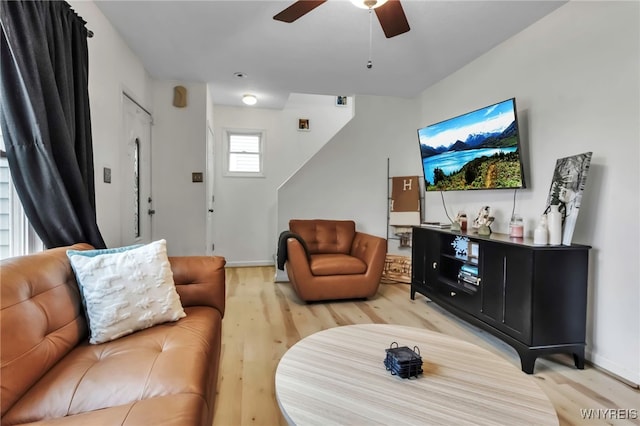 living room featuring ceiling fan, baseboards, and light wood-style floors