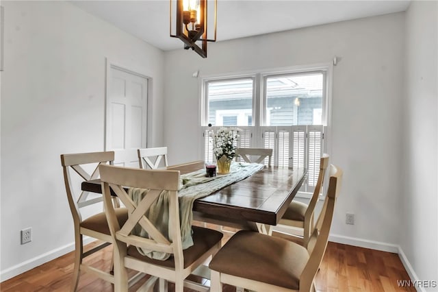 dining area featuring wood finished floors, a chandelier, and baseboards