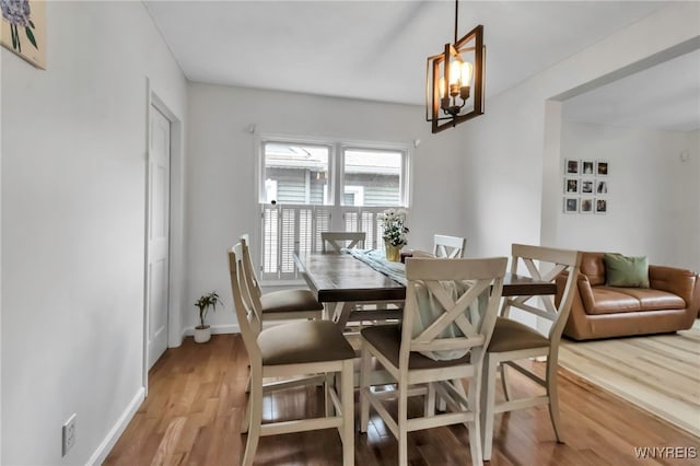dining area featuring a notable chandelier, light wood-style flooring, and baseboards