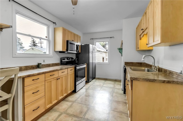 kitchen with a sink, light brown cabinets, dark countertops, appliances with stainless steel finishes, and light floors