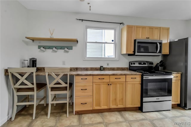 kitchen featuring light brown cabinets, light tile patterned floors, open shelves, appliances with stainless steel finishes, and dark countertops