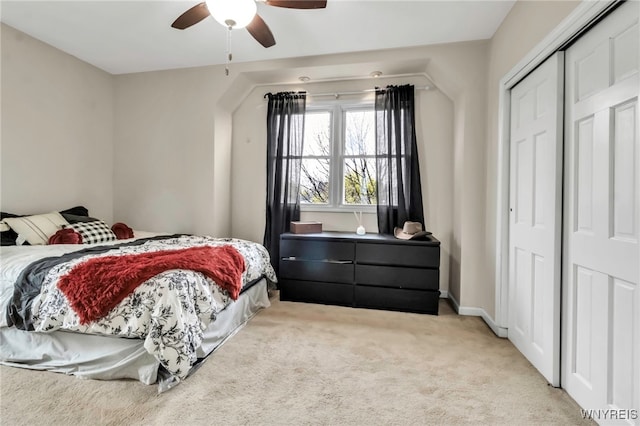 bedroom with a ceiling fan, light carpet, and a closet