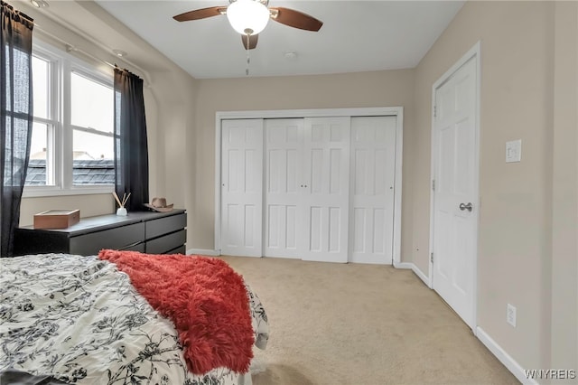 bedroom featuring a ceiling fan, a closet, light colored carpet, and baseboards