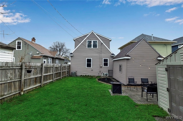 rear view of house with a patio area, a yard, cooling unit, a storage unit, and fence